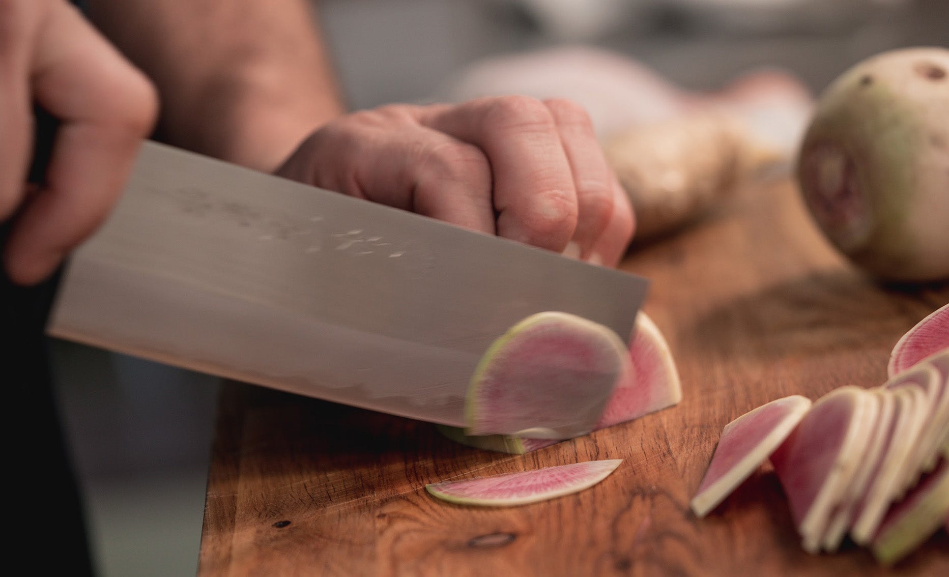 Chef cutting vegetables on a cutting board with a Nakiri knife