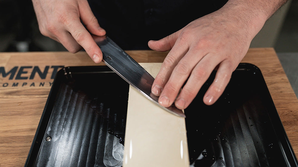 Person sharpening a knife on whetstone using Japanese methods.